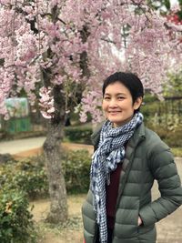 Portrait of a smiling young woman standing by flower trees