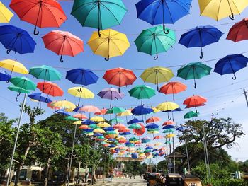 Low angle view of multi colored umbrellas hanging against sky