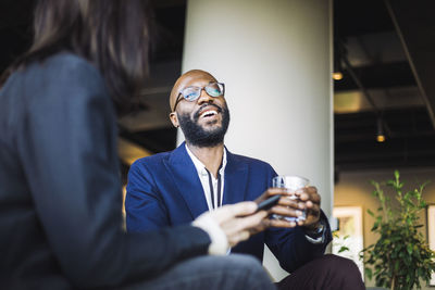 Smiling male entrepreneur looking away while sitting with female coworker in office