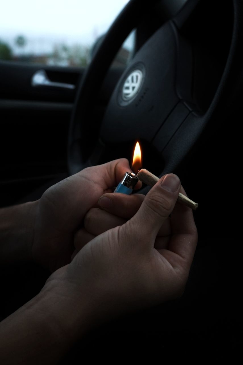 human hand, hand, human body part, burning, car, fire, one person, mode of transportation, holding, real people, flame, fire - natural phenomenon, motor vehicle, car interior, transportation, vehicle interior, body part, human finger, finger, indoors