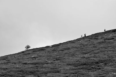 Low angle view of man walking on mountain against clear sky