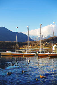 Sailboats moored in lake against sky