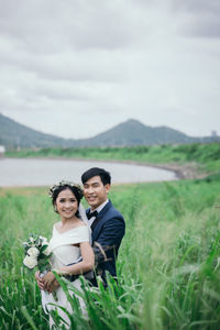 Young couple smiling on field against sky