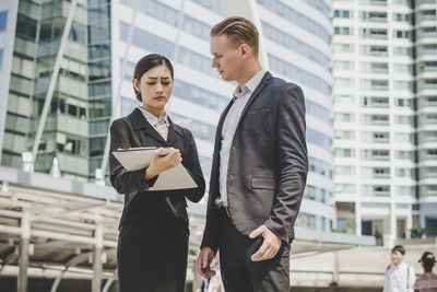 Low angle view of business people discussing while standing against building