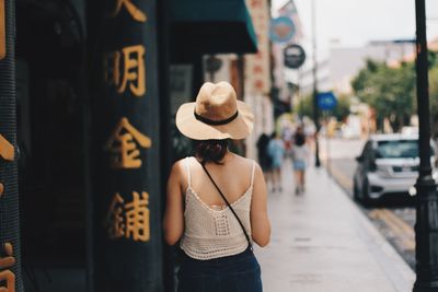 Rear view of woman wearing hat standing in city