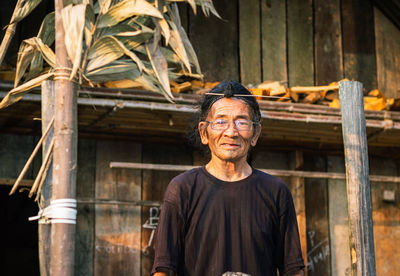 Senior man standing against hut