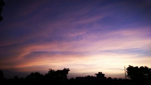 Silhouette trees against dramatic sky during sunset