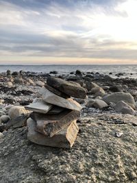 Rocks on beach against sky during sunset