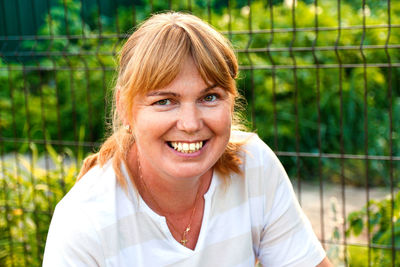 Portrait of smiling mature woman wearing stripe shirt and looking at camera. summer green nature 