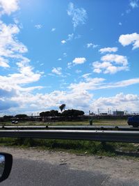 Road by railroad tracks in city against sky