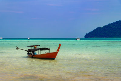 Boat moored on sea against sky
