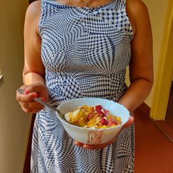 Midsection of woman holding bowl at home