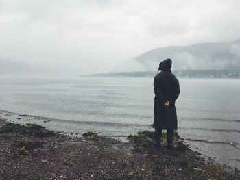 Rear view of man looking at sea against sky