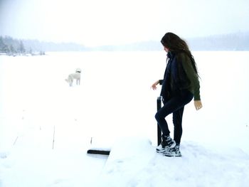 Side view of young woman on snow covered field