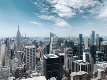 Aerial view of buildings in city against cloudy sky