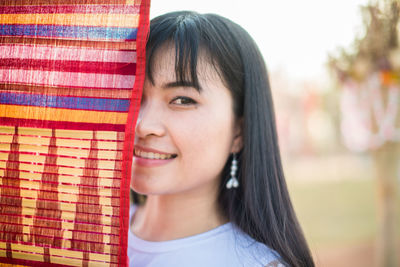 Close-up portrait of smiling young woman standing by colorful flag