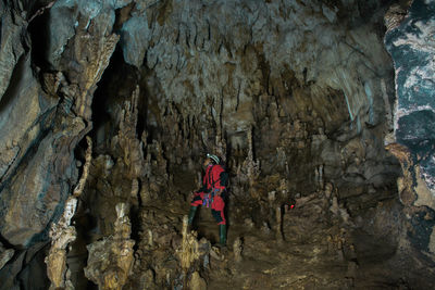 Rear view of woman standing on rock in cave