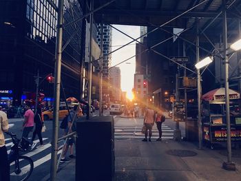 People walking on illuminated street amidst buildings in city at night