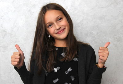 Portrait of smiling girl gesturing against wall