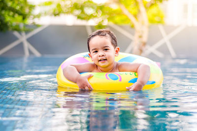 Portrait of boy with inflatable ring swimming in pool