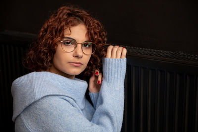 Portrait of young woman sitting against black background