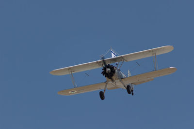 Low angle view of airplane against clear blue sky