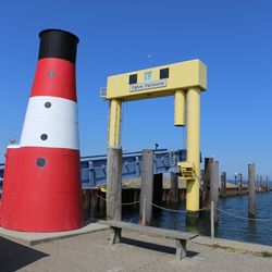 Lighthouse by sea against clear sky