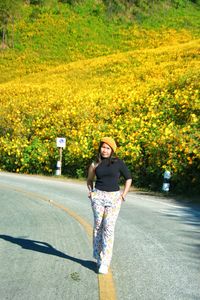 Full length portrait of smiling young woman on road