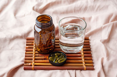 Omega 3 oil capsules and water glass on tray. fatty acids nutritional supplement for support health.