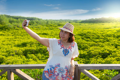 Woman standing by railing against sky