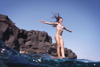 Smiling woman with arms outstretched jumping into water