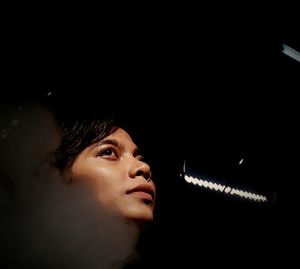 Low angle view of thoughtful young woman looking up seen through glass in darkroom