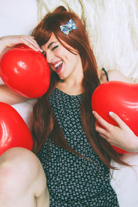 Portrait of smiling young woman holding balloons