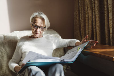 Senior woman with eyeglasses reading documents at home