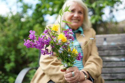 Portrait of smiling woman holding flowering plant