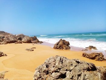 Scenic view of beach against clear blue sky