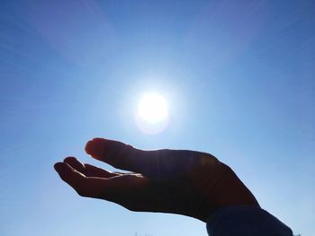 Midsection of person holding sun against clear blue sky