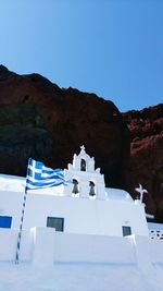 Low angle view of greek flag by bell tower against clear sky at santorini