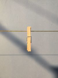 Close-up of clothespin hanging on clothesline against wall