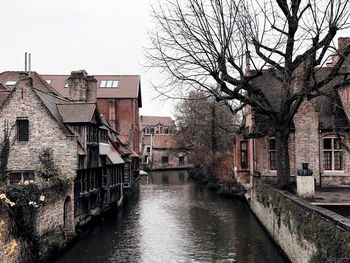 Canal amidst buildings in city against sky