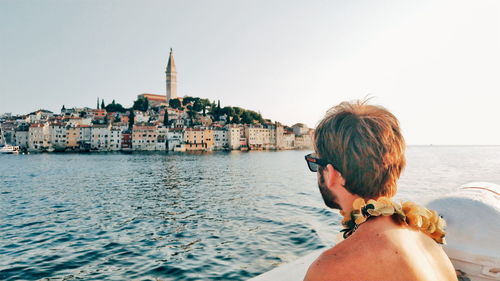 Rear view of woman looking at sea against buildings in city