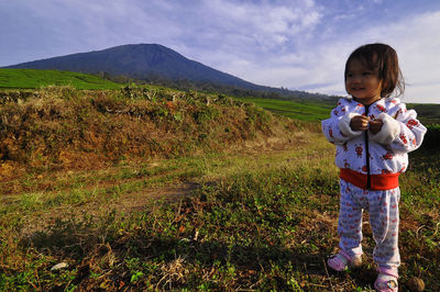 Boy standing on field against sky