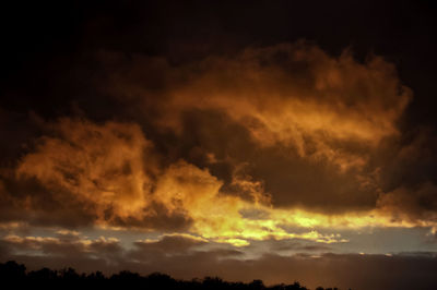 Low angle view of storm clouds at sunset