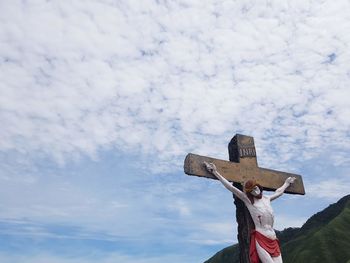 Low angle view of cross sculpture against sky