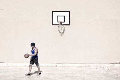 Man playing with basketball on court during sunny day