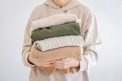 Woman's hand holding a stack of clothes. clothes donation, renewable concept. washing, decluttering 