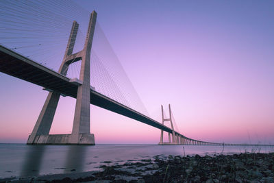 Low angle view of bridge over sea at sunset