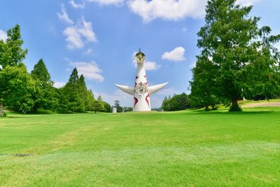 Man sculpture on field against sky