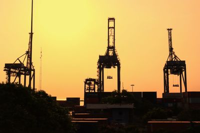 Silhouette of a factory against sky during sunset