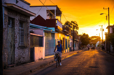 Man riding bicycle on road amidst buildings in city